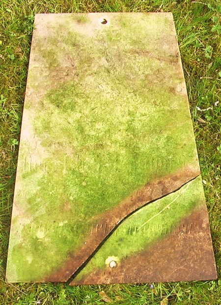 weathered memorial plate broken by ivy